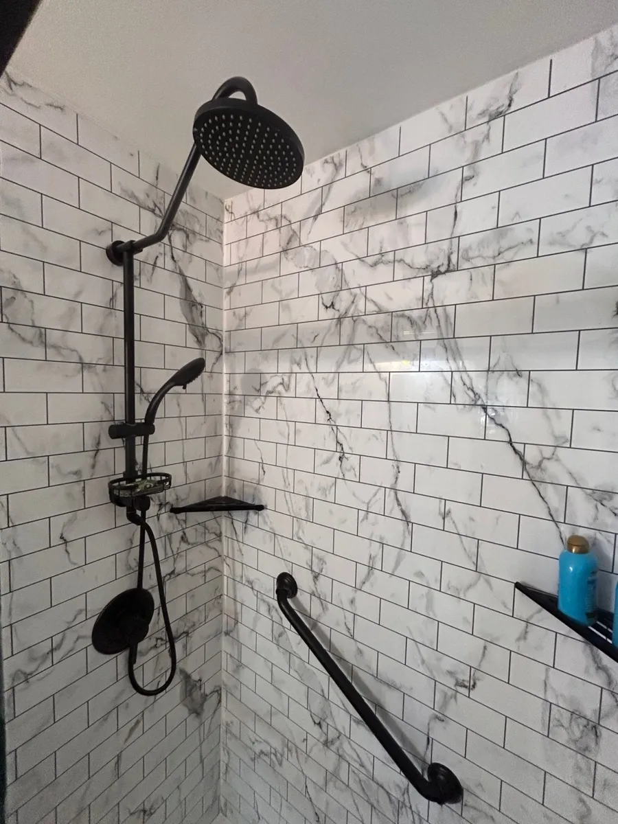 Walk-in shower detail with matte black rain showerhead, handheld sprayer, and grab bar